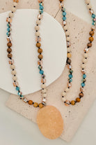 Three beaded necklaces on a textured surface with a neutral background