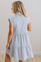 Woman wearing a blue and white striped dress against a plain background