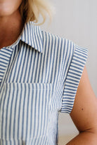 Close-up of a person wearing a blue and white striped shirt with a plain background