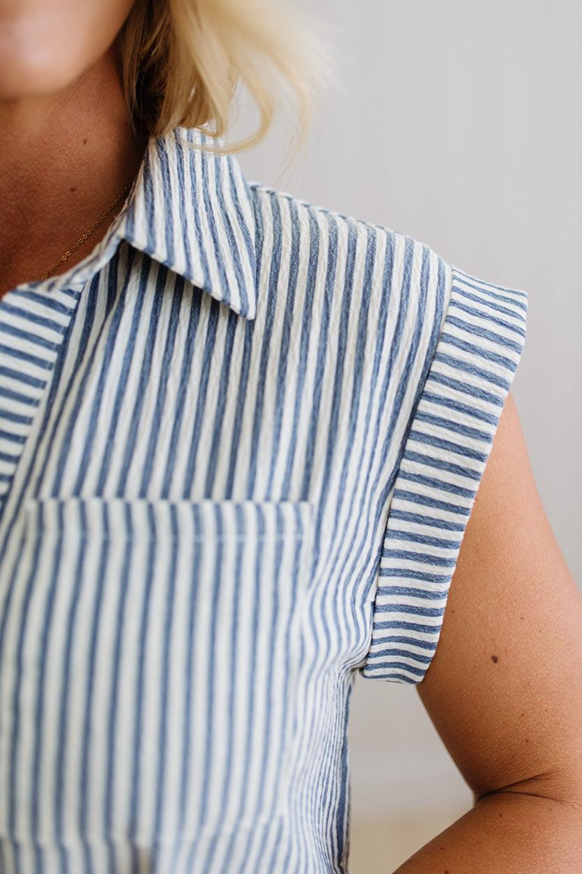 Close-up of a person wearing a blue and white striped shirt with a plain background