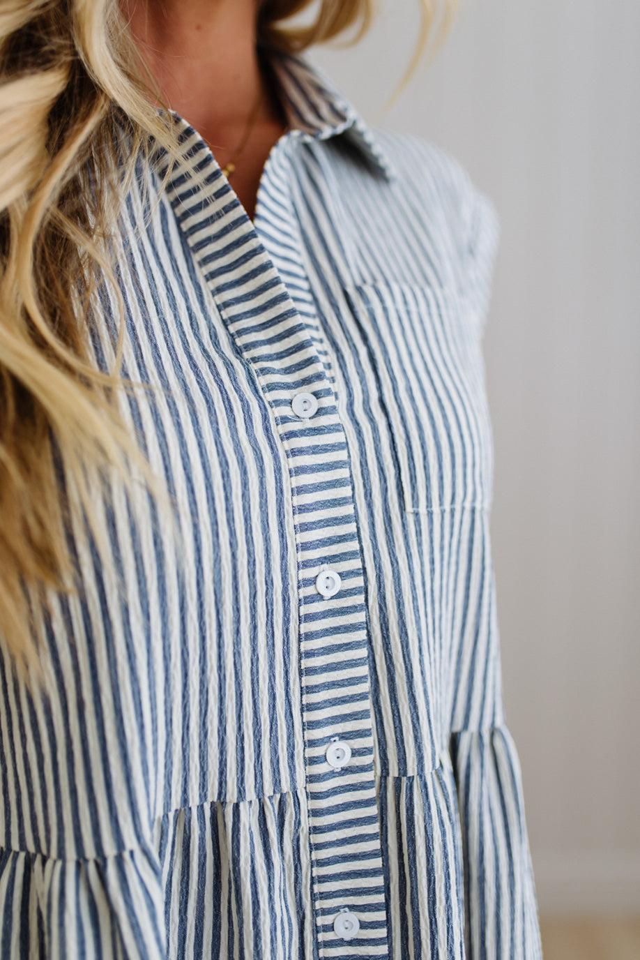 Blue and white striped dress worn by a person with a neutral background