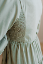 Light green dress with smocked back detail on a neutral background