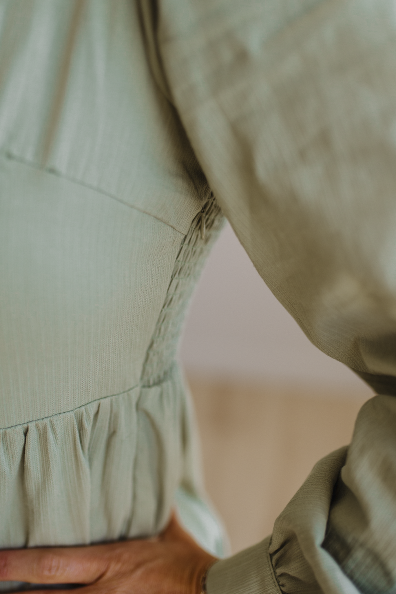 Close-up of a person wearing a beige jacket with a blurred background