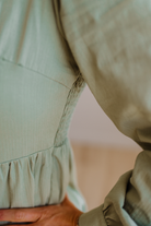 Close-up of a person wearing a beige jacket with a blurred background