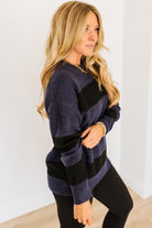 Woman wearing a navy and black striped sweater against a white background