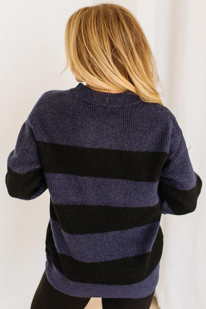 Person wearing a black and purple striped sweater against a white background
