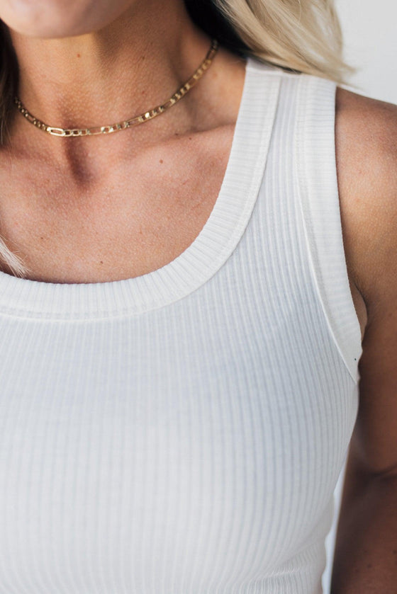 Woman wearing a white crop length, scoop neck tank top,