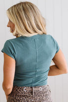 Woman wearing a teal top with a white background