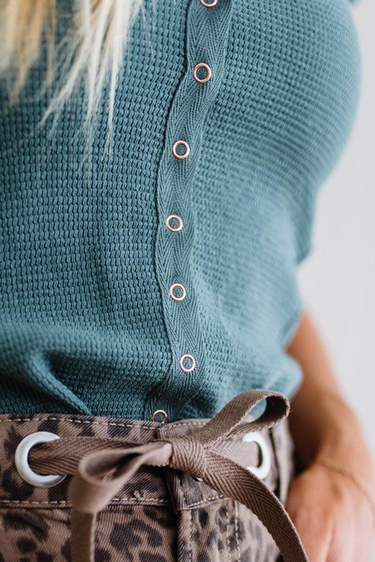 Teal knitted top with button details and leopard print pants.