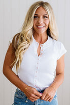 Woman wearing a white blouse and blue jeans against a plain background