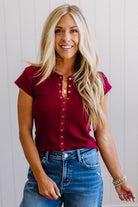 Woman wearing a red top and blue jeans against a white background
