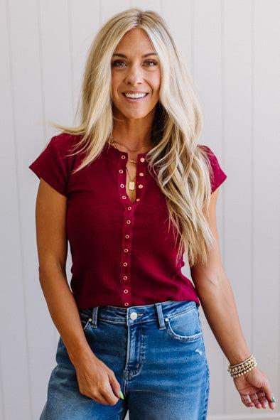 Woman wearing a red top and blue jeans against a white background