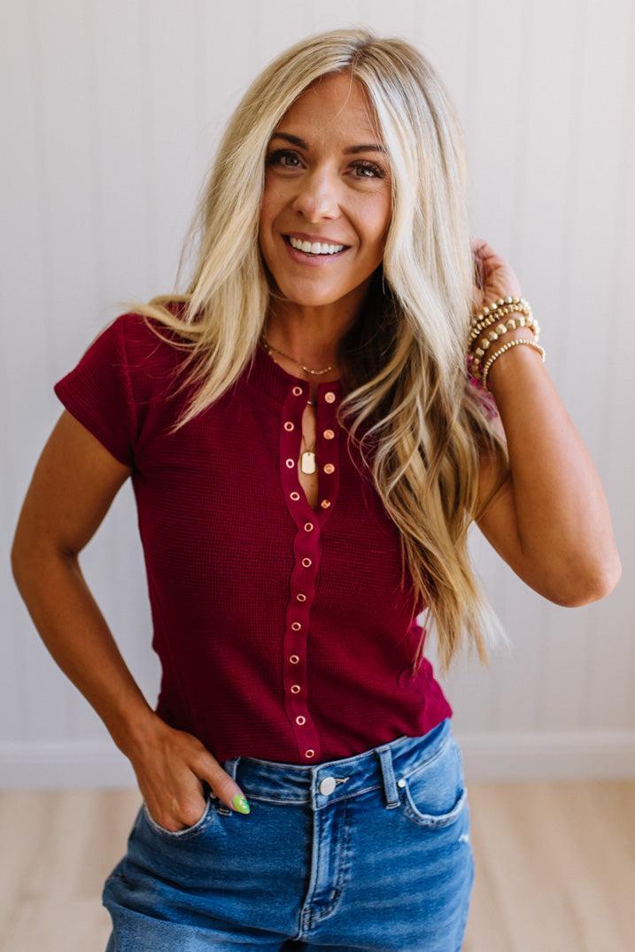 Woman wearing a red shirt and blue jeans with a neutral background