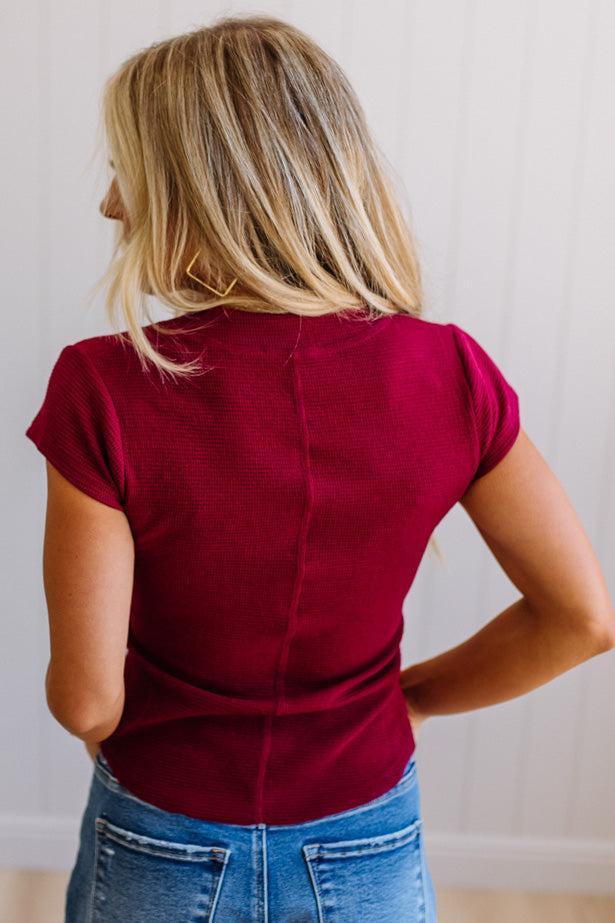 Woman wearing a red top and blue jeans against a plain background
