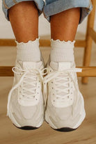 White sneakers with black soles worn with light blue denim shorts and white socks.