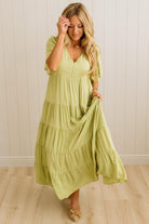 Woman wearing a light green dress with a white paneled wall background