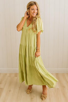 Woman wearing a light green dress standing against a white wall.