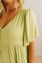 Woman wearing a light green dress with a plain background