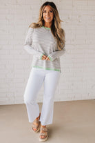 Blonde woman wearing a lightweight sweater with grey and white stripes with light green trim at neckline, wrist and hem.