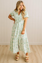 Woman wearing a floral dress standing against a plain background