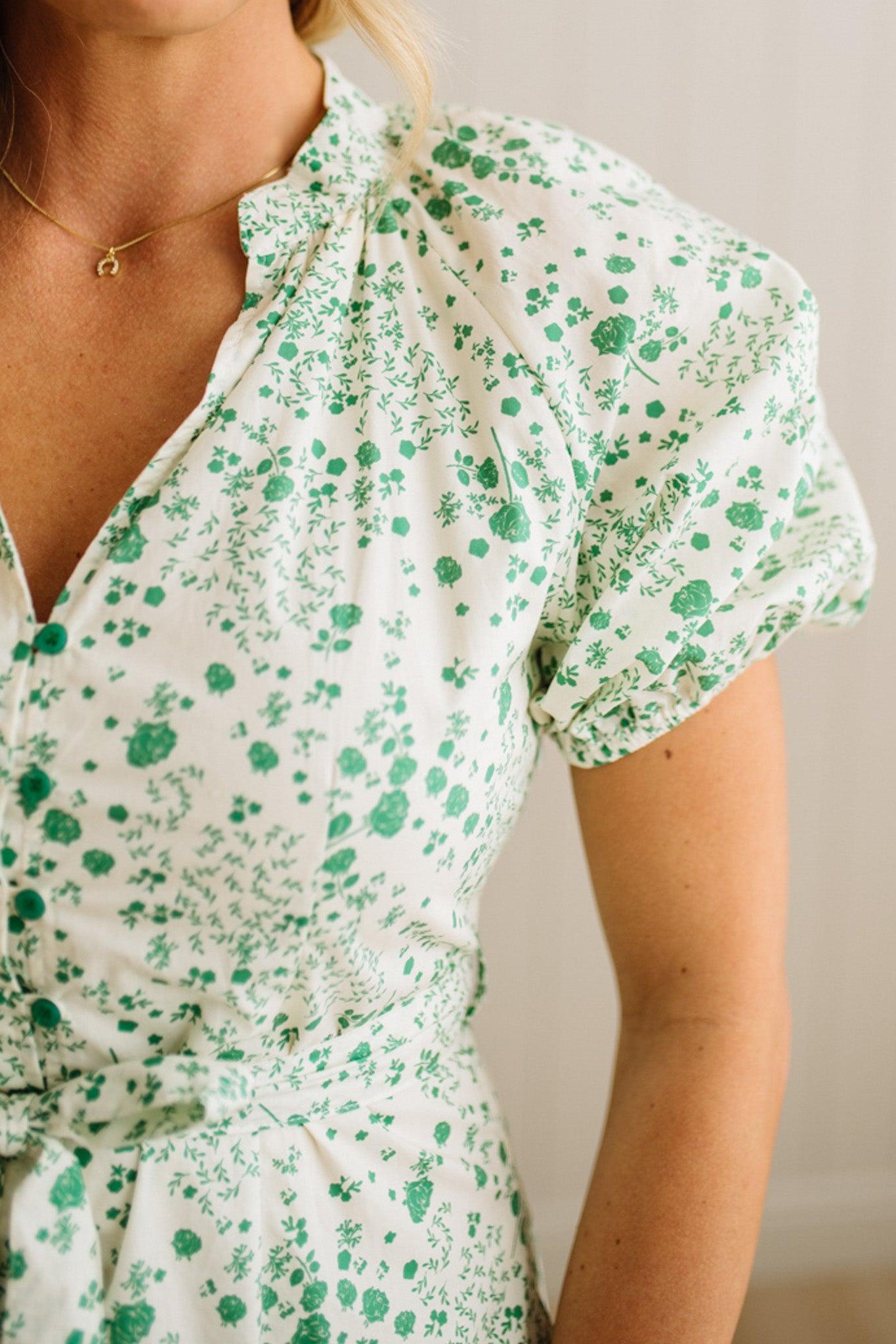 Woman wearing a green floral dress against a neutral background