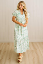 Woman wearing a floral dress standing against a plain background