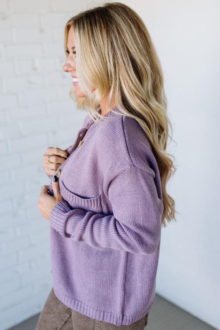 Woman wearing a purple sweater against a white wall
