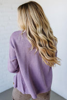 Person wearing a purple sweater with a plain background