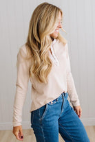 BLONDE WOMAN IN A BRIGHTLY LIT STUDIO WEARING DARK JEANS AND A SATIN RUCHED TRIM HALF BUTTON NECK, LONG SLEEVE, SOLID TOP IN IVORY