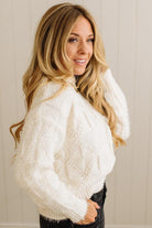 Woman wearing a white cable knit sweater against a neutral background