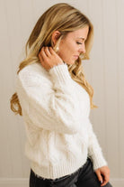 Woman wearing a white sweater against a plain background
