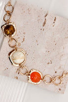 Interconnected Gold Ring Bracelet With Resin Marble Beads on a stone surface.