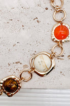 Interconnected Gold Ring Bracelet With Resin Marble Beads on a stone surface.