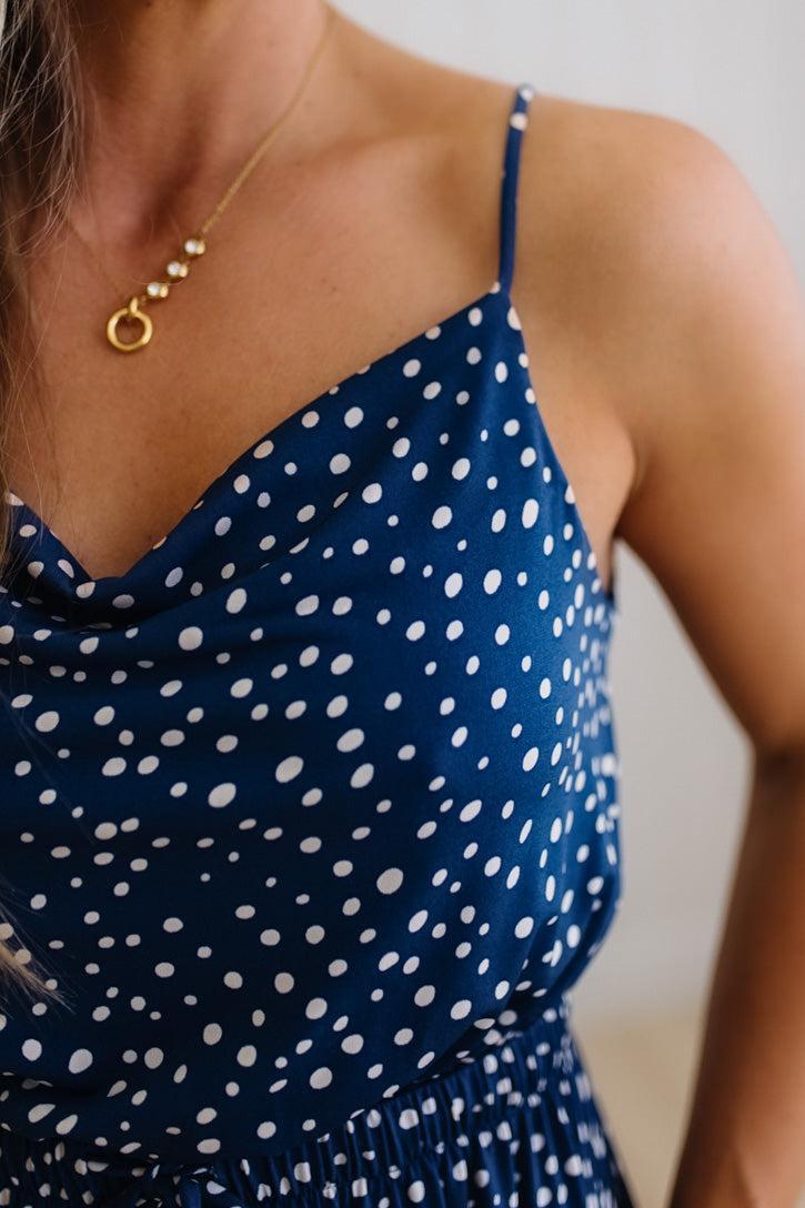 Navy blue dress with white polka dots worn by a person, with a gold necklace visible.
