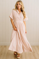 Woman wearing a pink and white striped dress against a light wooden paneled wall.