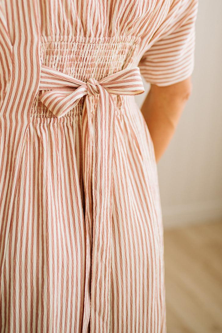 Close-up of a person wearing a striped dress with a bow detail.
