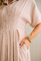 Person wearing a pink and white striped dress with a neutral background