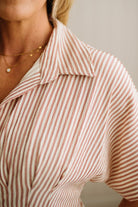 Close-up of a person wearing a pink and white striped shirt with a blurred background