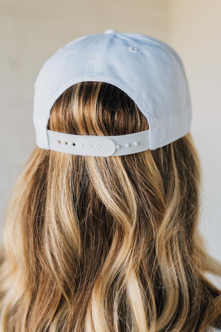Person wearing a white cap with a white strap on a neutral background