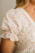 Floral blouse with ruffled sleeves worn by a person, against a neutral background