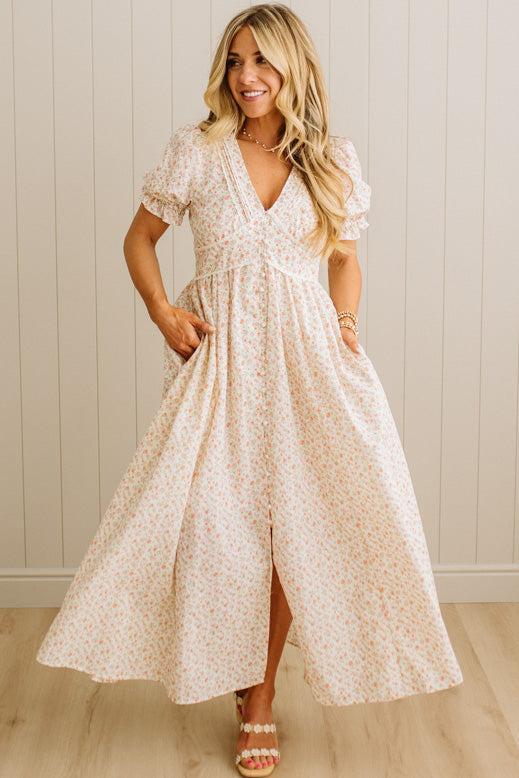 Woman wearing a floral dress standing against a neutral background