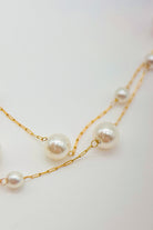 Pearl necklace with gold chain on a light background