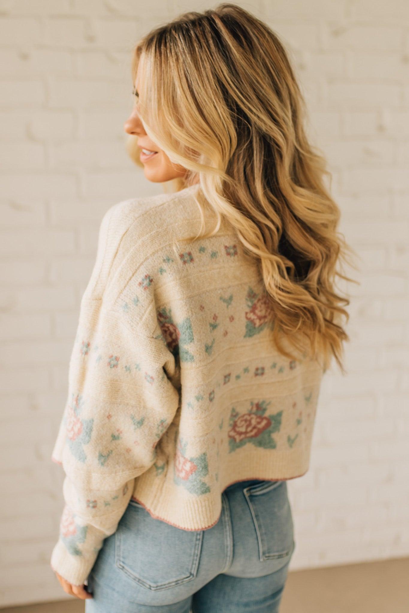 Woman wearing a floral cardigan and jeans against a plain background