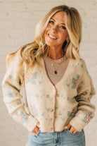 Woman wearing a patterned beige cardigan with a neutral background