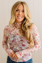 Woman wearing a floral long-sleeve top against a plain background