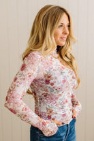 Woman wearing a floral long-sleeve top against a plain background