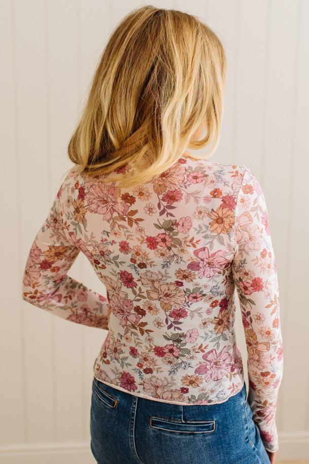 Person wearing a floral long-sleeve top with a neutral background