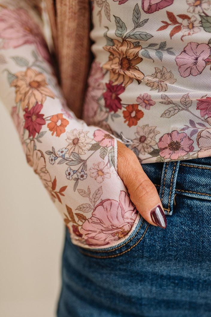 Person wearing a floral long-sleeve top with a neutral background