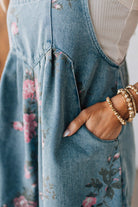 BLONDE WOMAN WEARING FLOWER PRINT WASHED DENIM WIDE LEG SHORTALLS WITH ADJUSTABLE BUTTONED SHOULDER STRAP