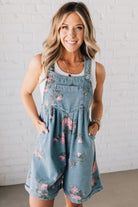 BLONDE WOMAN WEARING FLOWER PRINT WASHED DENIM WIDE LEG SHORTALLS WITH ADJUSTABLE BUTTONED SHOULDER STRAP